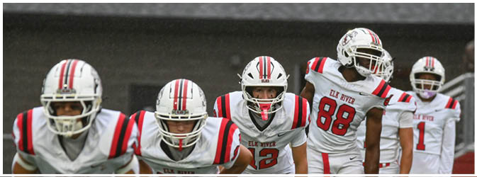 A football game is taking place on a field with players wearing blue and white uniforms. Description generated by AI