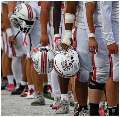 A football game is taking place with a group of men on the field. Description generated by AI