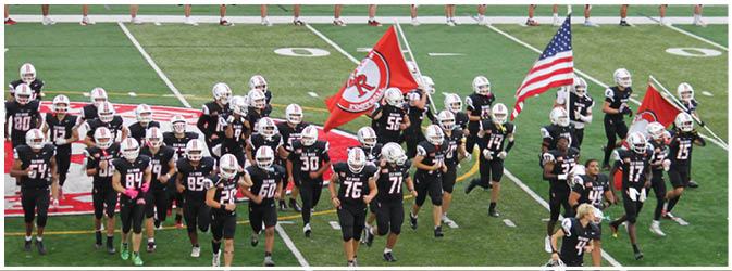 A football game is taking place on a field with players wearing blue and white uniforms. Description generated by AI