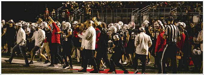 A football game is taking place on a field with players wearing blue and white uniforms. Description generated by AI