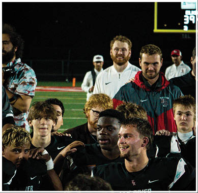 A football game is taking place with a group of men on the field. Description generated by AI