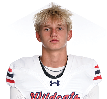 A person with tousled blond hair wearing a white Wildcats football jersey with the number seven stands facing forward against a plain white background. Description generated by AI