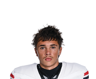 A person with curly hair wearing a white football jersey with red and black stripes on the sleeves and the word Wildcats across the chest stands facing forward. Description generated by AI