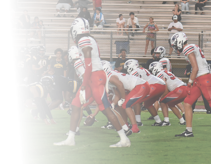 People in sports uniforms are on a field with spectators sitting on bleachers in the background. Description generated by AI
