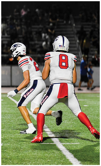 A person wearing a white football uniform with the number 8 on the back is running on a green field during a game. Description generated by AI