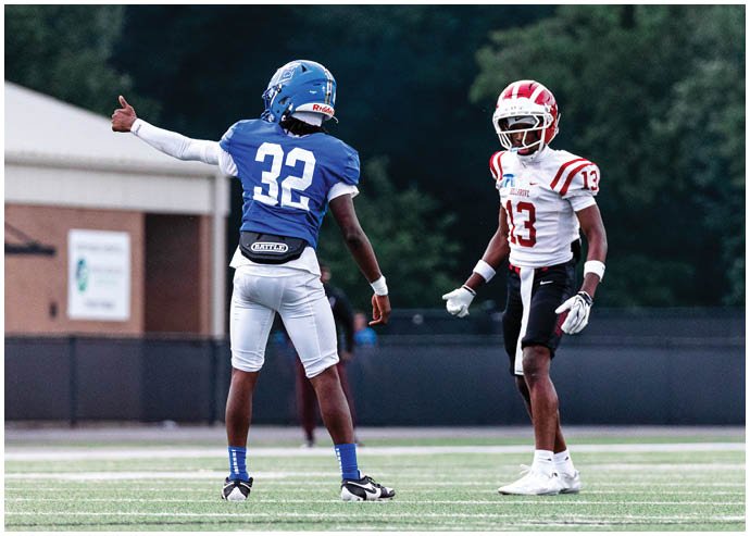 Three football players in blue and white uniforms running on a field. Description generated by AI