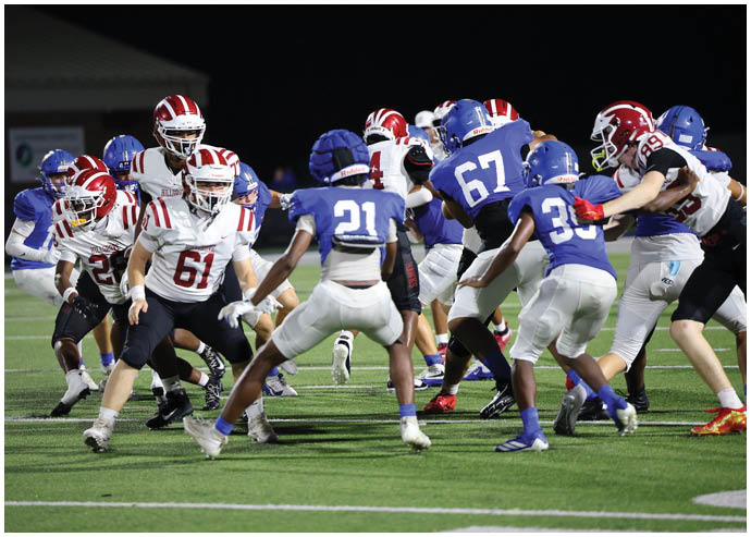 Three football players in blue and white uniforms running on a field. Description generated by AI