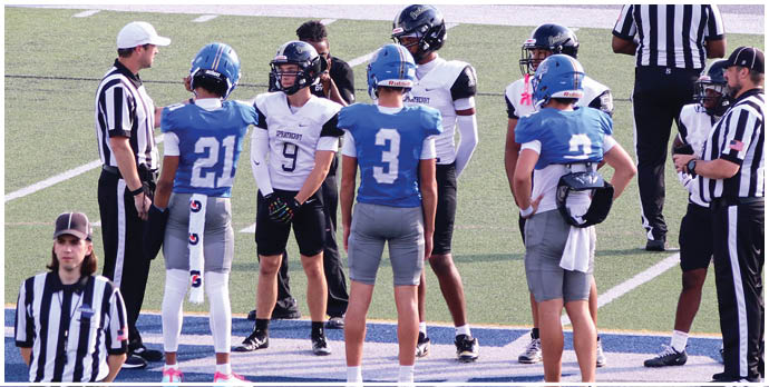 Three football players in blue and white uniforms running on a field. Description generated by AI