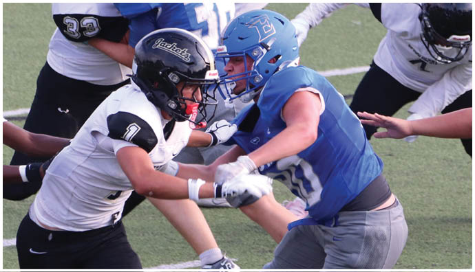 Three football players in blue and white uniforms running on a field. Description generated by AI