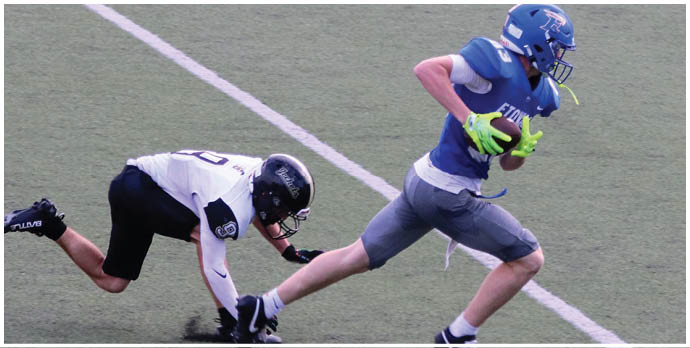 Three football players in blue and white uniforms running on a field. Description generated by AI