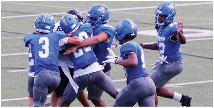 Three football players in blue and white uniforms running on a field. Description generated by AI