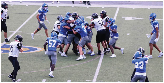 Three football players in blue and white uniforms running on a field. Description generated by AI