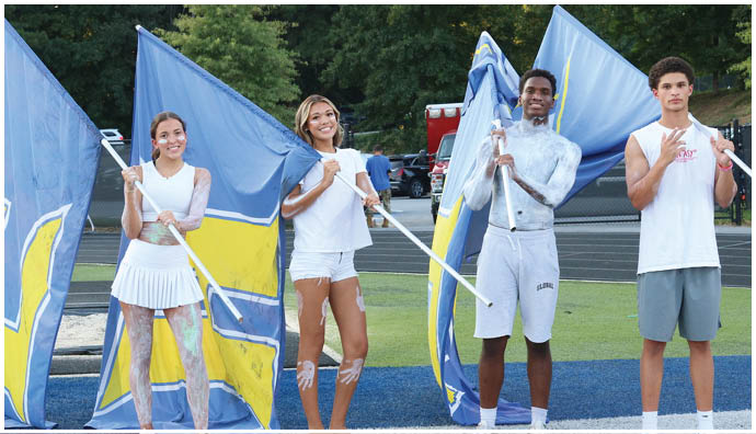 Three football players in blue and white uniforms running on a field. Description generated by AI