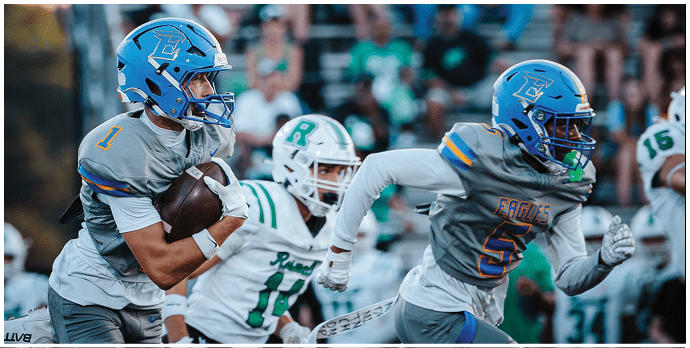 Three football players in blue and white uniforms running on a field. Description generated by AI