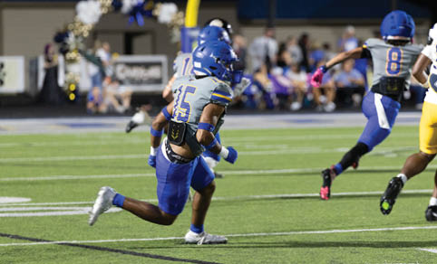 Two men wearing football uniforms are hugging each other on a field. AI generated content