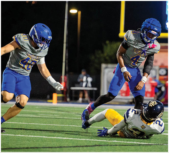 Three football players in blue and white uniforms running on a field. Description generated by AI