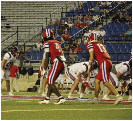 A group of football players huddled together on the field. Description generated by AI