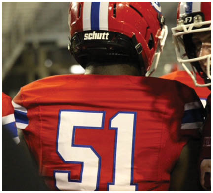 A group of football players huddled together on the field. Description generated by AI