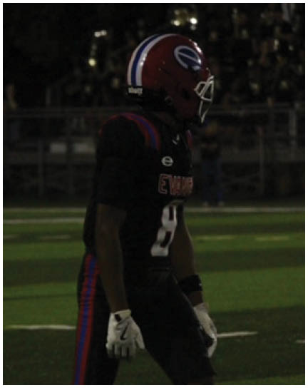 A football player wearing a blue and white uniform. Description generated by AI