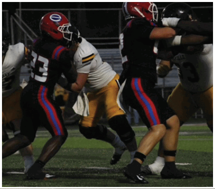 A group of football players huddled together on the field. Description generated by AI