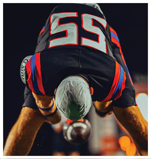 Two football players wearing black jerseys and holding hands. Description generated by AI