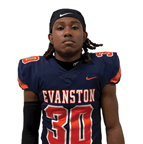 Person wearing a dark sports jersey with orange and white details and a black headband looking directly at the camera. Description generated by AI