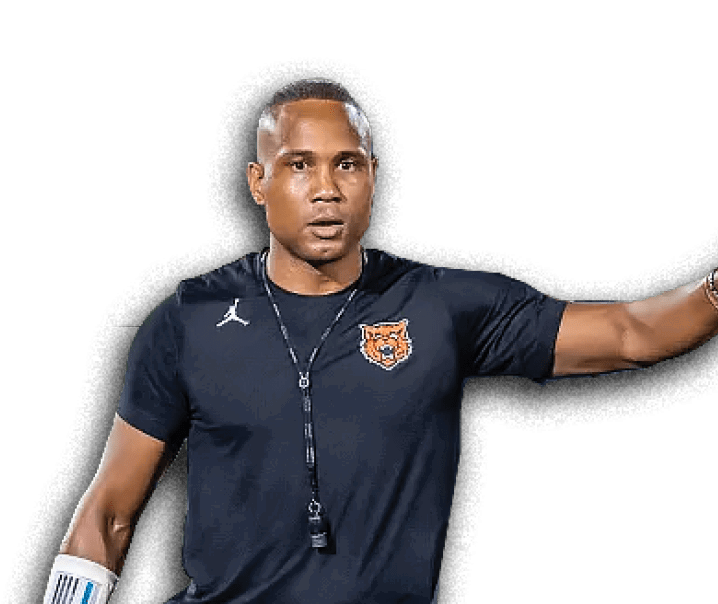 Person wearing a dark sports shirt with a tiger logo and a whistle around their neck is gesturing with one arm extended. Description generated by AI