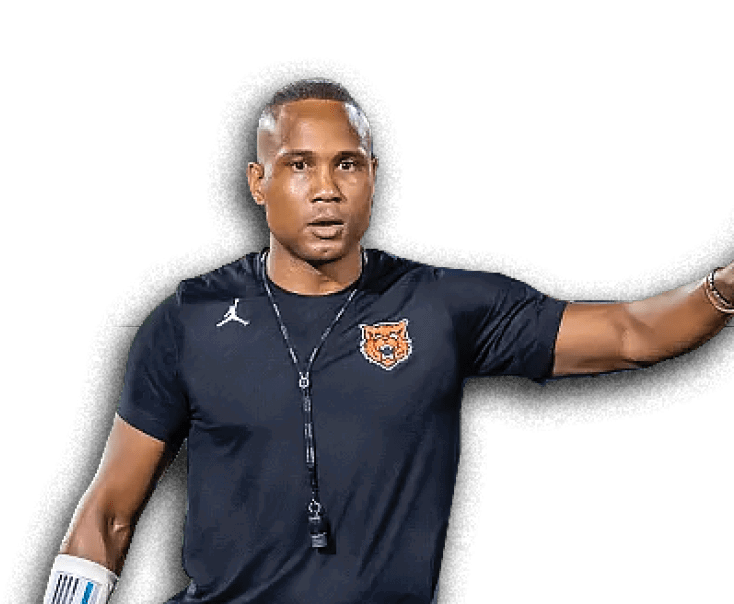 Person wearing a dark sports shirt with a tiger logo and a whistle around their neck is gesturing with one arm extended. Description generated by AI