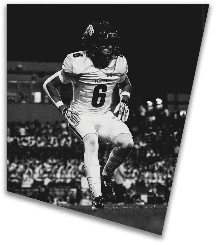 A person wearing a dark football uniform and helmet with “American Canyon" on the jersey is kneeling on one knee on a field at night. Description generated by AI