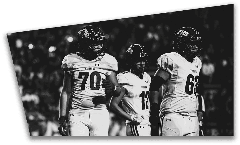 People wearing black American Canyon football uniforms and helmets are standing on a football field at night. Description generated by AI
