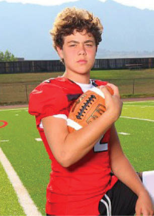 A young man wearing a white and black jersey with the number 14 on it. Description generated by AI