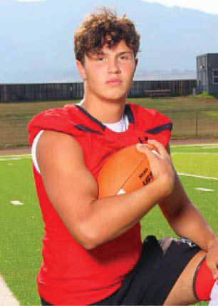 A young man wearing a white and black jersey with the number 14 on it. Description generated by AI