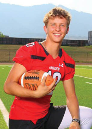 A young man wearing a white and black jersey with the number 14 on it. Description generated by AI