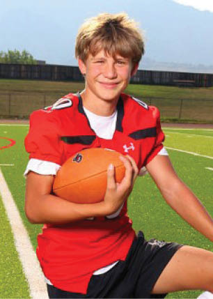 A young man wearing a white and black jersey with the number 14 on it. Description generated by AI
