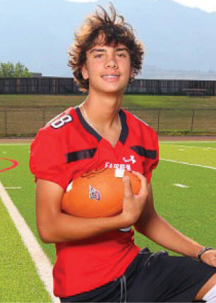 A young man wearing a white and black jersey with the number 14 on it. Description generated by AI