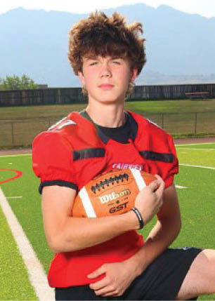 A young man wearing a white and black jersey with the number 14 on it. Description generated by AI