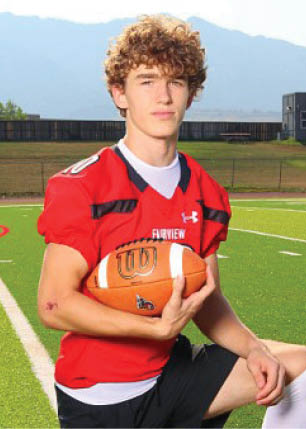 A young man wearing a white and black jersey with the number 14 on it. Description generated by AI