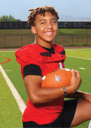 A young man wearing a white and black jersey with the number 14 on it. Description generated by AI