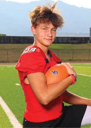 A young man wearing a white and black jersey with the number 14 on it. Description generated by AI