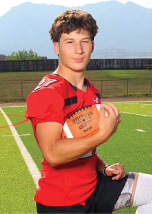 A young man wearing a white and black jersey with the number 14 on it. Description generated by AI