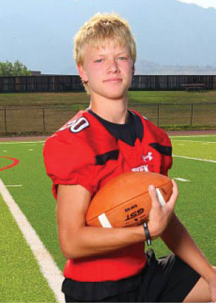 A young man wearing a white and black jersey with the number 14 on it. Description generated by AI