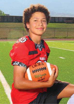 A young man wearing a white and black jersey with the number 14 on it. Description generated by AI