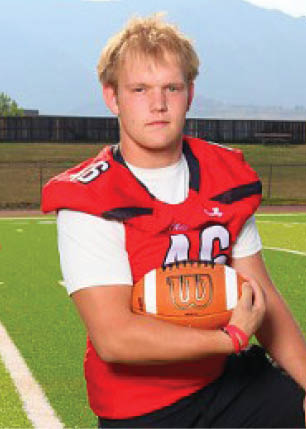 A young man wearing a white and black jersey with the number 14 on it. Description generated by AI