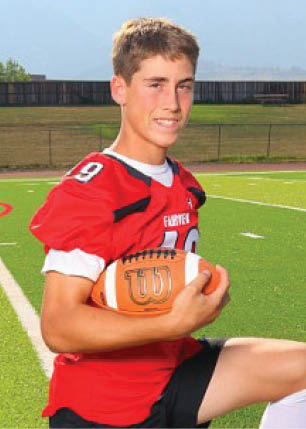 A young man wearing a white and black jersey with the number 14 on it. Description generated by AI