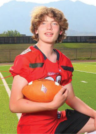 A young man wearing a white and black jersey with the number 14 on it. Description generated by AI