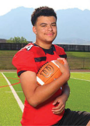 A young man wearing a white and black jersey with the number 14 on it. Description generated by AI