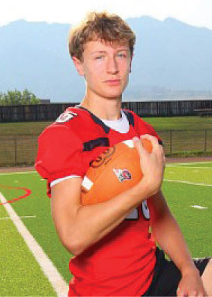 A young man wearing a white and black jersey with the number 14 on it. Description generated by AI