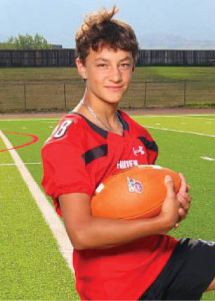 A young man wearing a white and black jersey with the number 14 on it. Description generated by AI