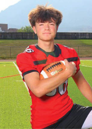 A young man wearing a white and black jersey with the number 14 on it. Description generated by AI