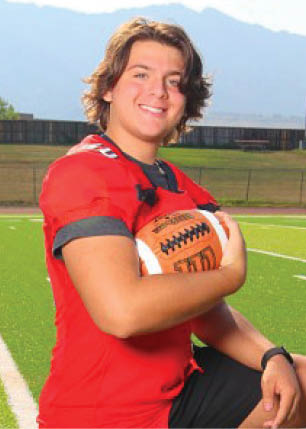 A young man wearing a white and black jersey with the number 14 on it. Description generated by AI